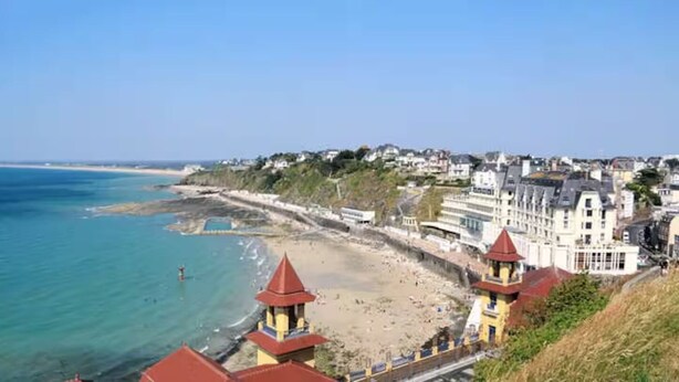 Une ville côtière avec une plage, des bâtiments et un phare.