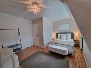 A bedroom with a bed, bedside tables, a desk, a chair, a ceiling fan, and a door. - Au Mont Chez Nous #Jacuzzi and Sauna (Pontorson)