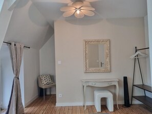 A room with a ceiling fan, a mirror, a desk, a chair, and a radiator. - Au Mont Chez Nous #Jacuzzi and Sauna (Pontorson)