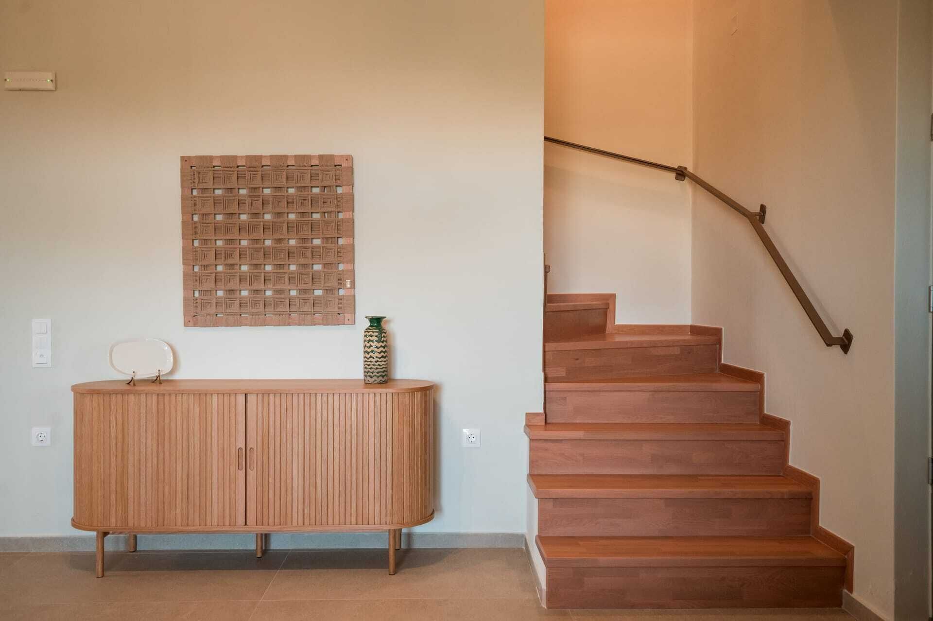 A wooden staircase with a handrail and a wooden panel wall with a geometric pattern.