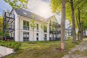 Um edifício moderno com várias varandas e um gramado bem cuidado.