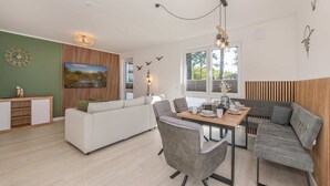 Un salon moderne comprenant un canapé, une table à manger et des chaises, un meuble en bois et une grande fenêtre offrant une belle vue.