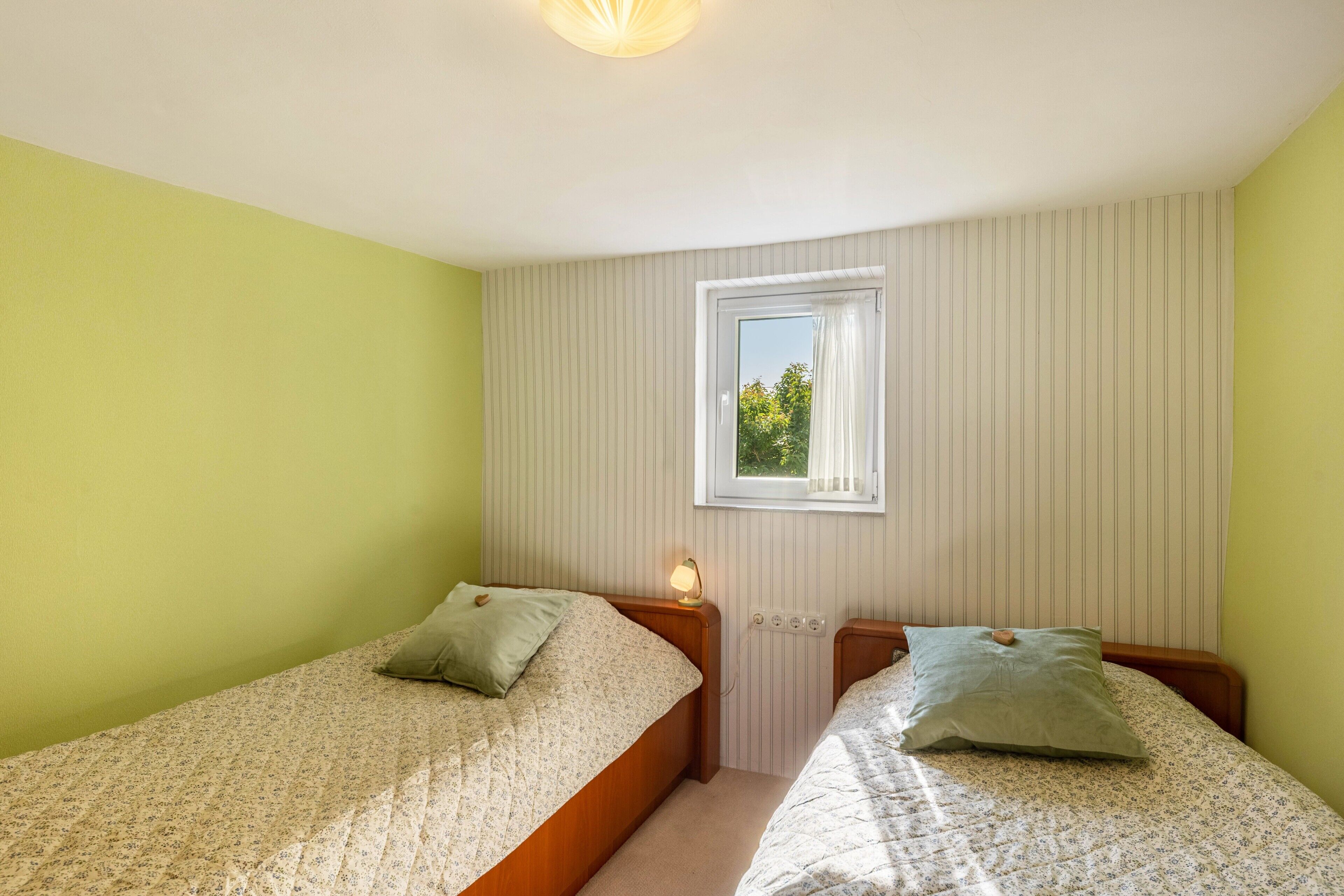 A bedroom with two beds, a window with a view, and a light fixture.