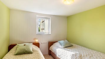 Een kamer met twee bedden, een raam, een lamp en een deur.