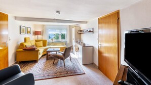 Un espai vital reduït amb sofà, taula petita, televisió i cuina americana.