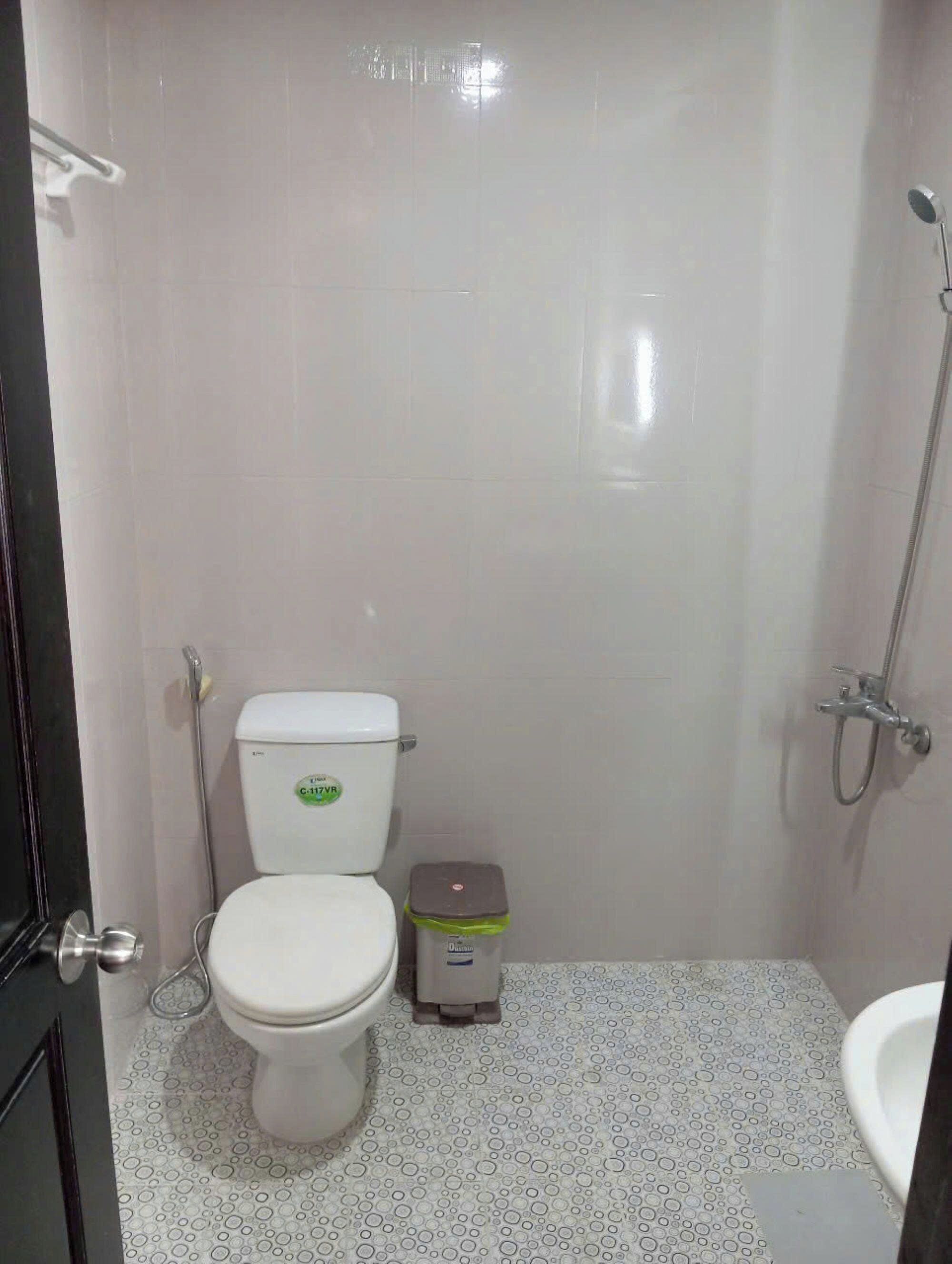 Un baño pequeño y limpio con inodoro, un cubo de basura y ducha.