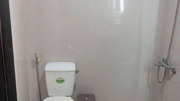 Un baño pequeño y limpio con inodoro, un cubo de basura y ducha.