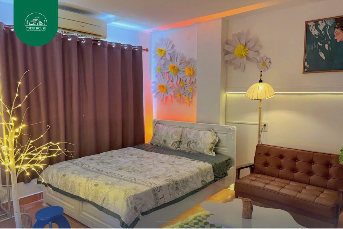 A bedroom with a bed, a brown leather sofa, a wall with floral decorations, and a ceiling fan.