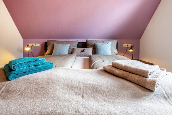 A bedroom with a bed, pillows, and folded towels.