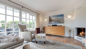 A modern living room with a fireplace, a large window, and a painting on the wall. - Sölring Juwel Whg. 1 - Relaxed living in the Sölring Juwel Whg. 1 in (Wenningstedt-Braderup (Sylt))