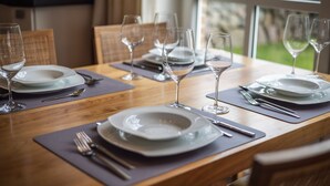 A dining table set with plates, cutlery, and wine glasses, with a view of greenery outside. - Sölring Juwel Whg. 1 - Relaxed living in the Sölring Juwel Whg. 1 in (Wenningstedt-Braderup (Sylt))