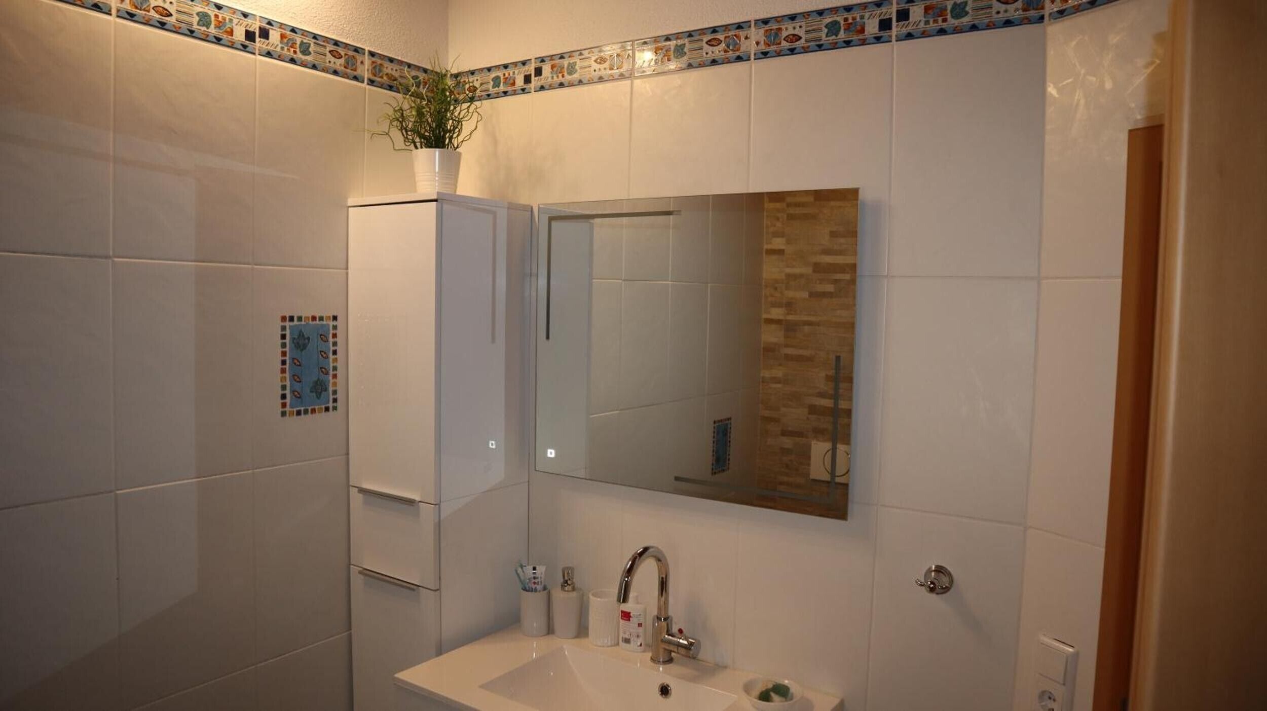 Ein Badezimmer mit Waschbecken, Spiegel und Schrank.