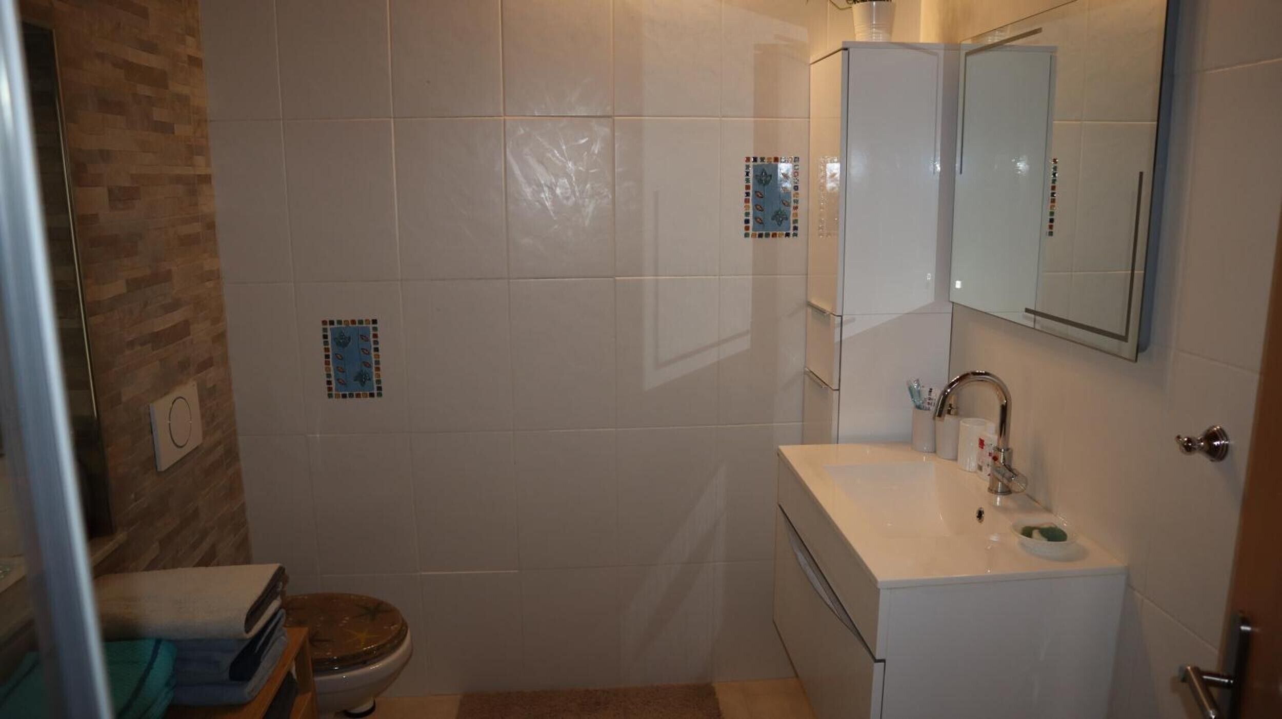 Une salle de bain équipée de toilettes, d’un lavabo, d’un miroir et d’un espace douche.