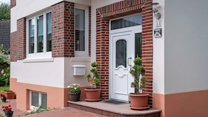 Um edifício com porta branca, caixa de correio e plantas em vasos.