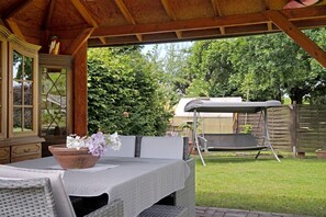 An outdoor patio with a table, chairs, a wicker sofa, and a swing set.
