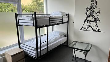 Habitación con literas, una mesita pequeña y un radiador.