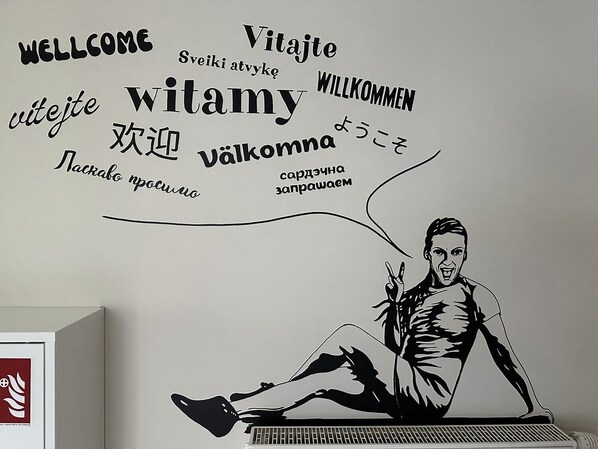 A wall with a man sitting on a piano, surrounded by words in multiple languages. - Mololo Art Hostel (Sopot)
