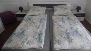 A twin bed with floral bedding, two bedside tables with lamps, and a small purple bench. - Apartment '4-Raum Ferienwohnung' with Shared Terrace and Wi-Fi (Cuxhaven)