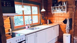 Une cuisine de style rustique, avec des murs en bois, une grande fenêtre, un poêle et un évier.