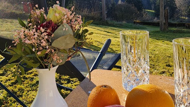 A table with a white vase, two oranges, and an apple. - Ferienhaus Alte Schmiede – Titisee Apartment with Feldberg View (Feldberg (Schwarzwald))