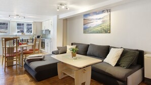 A modern living space with a sofa, a small table, and a dining area with chairs. - Ferienhaus Alte Schmiede – Titisee Apartment with Feldberg View (Feldberg (Schwarzwald))