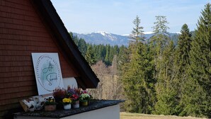 A building with a sign, potted plants, and a view of snow-capped mountains. - Ferienhaus Alte Schmiede – Titisee Apartment with Feldberg View (Feldberg (Schwarzwald))