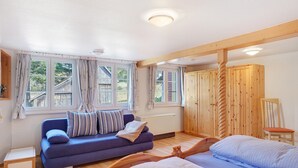 A room with a blue sofa, a wooden bed, and a wooden wardrobe. - Ferienhaus Alte Schmiede – Titisee Apartment with Feldberg View (Feldberg (Schwarzwald))