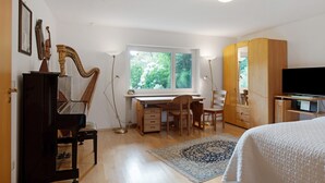 Une chambre à coucher comprenant un lit, un bureau avec une chaise, un piano, une télévision et une armoire.