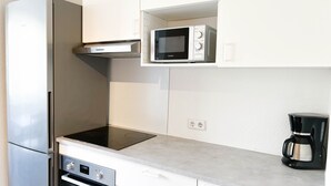 Una cocina con un refrigerador de acero inoxidable, un microondas, un horno y una cafetera.