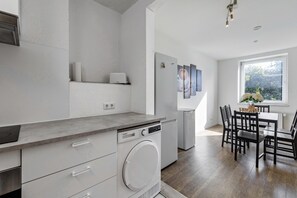 Une cuisine moderne équipée d’un lave-vaisselle, d’un lave-linge encastré et d’un coin repas avec une table et des chaises.