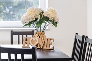 Ein Esstisch mit einer Blumenvase und Holzbuchstaben, die das Wort 'HOME' bilden.