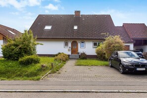 Une maison à deux étages, avec un toit en tuiles, une porte d’entrée et une allée.