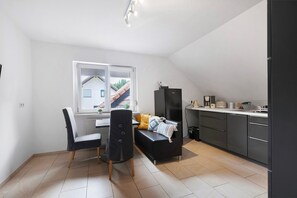 Une cuisine compacte avec un coin repas, un réfrigérateur noir et une fenêtre donnant sur une maison.