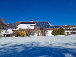 Una casa con techo nevado, paneles solares y un cielo azul despejado.