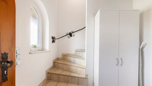 Een trap met beige tegels, een witte deur en een klein raam met een plant.