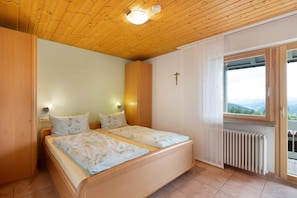 Un dormitorio con techo de madera, dos camas, un radiador y una ventana con vistas.