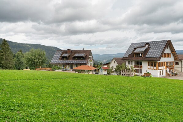 Une maison de campagne dotée de panneaux solaires, d’un jardin et située dans un cadre montagneux.
