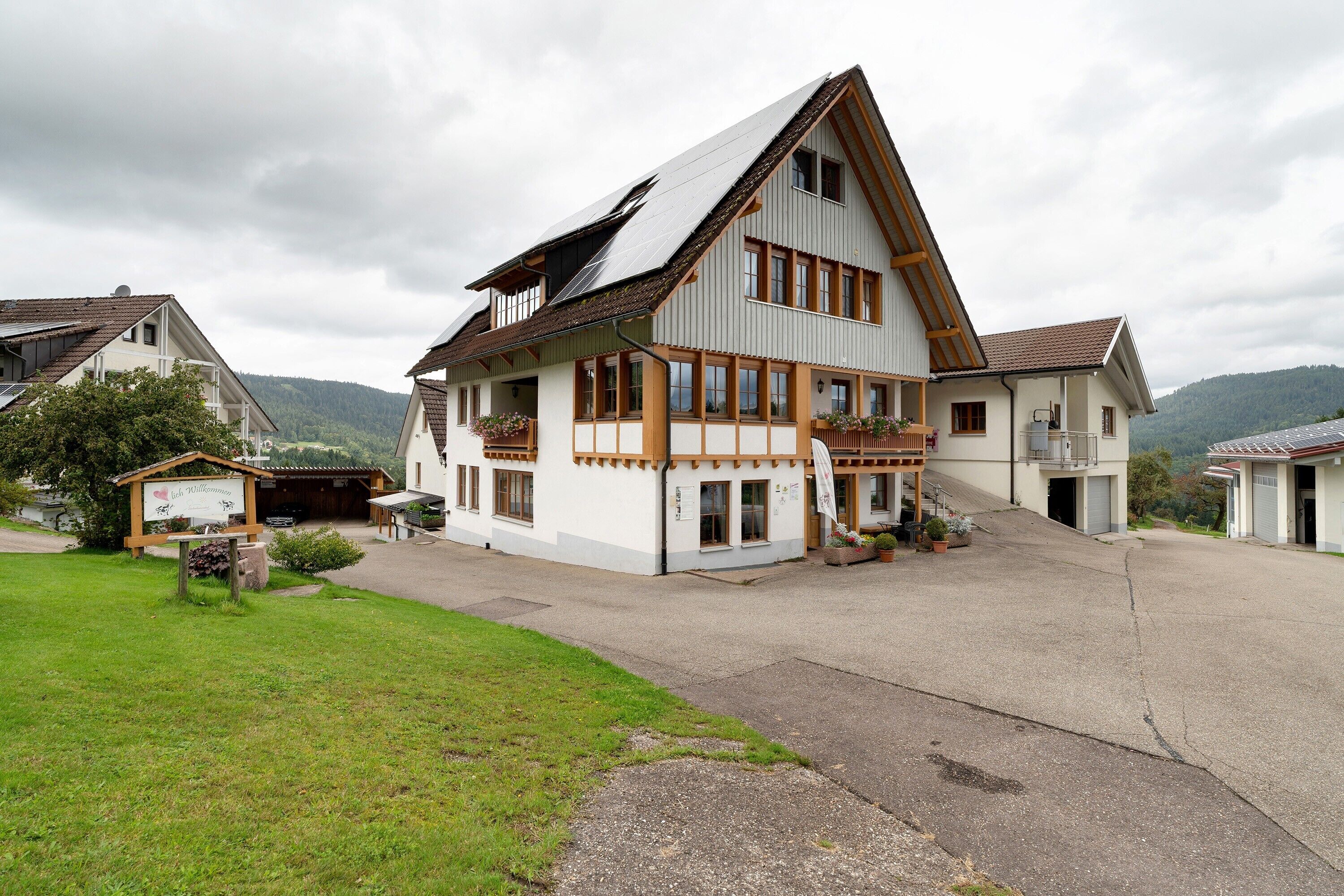 Ein zweigeschossiges Haus mit einem geneigten Dach, einem Balkon und einer Garage.