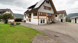 Ein zweigeschossiges Haus mit einem geneigten Dach, einem Balkon und einer Garage.