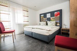 A modern bedroom with a bed, two chairs, a bedside table, and a wall with a floral artwork. - Löcherhansenhof: Apartment '4' with Mountain View, Shared Terrace and Wi-Fi (Bad Peterstal-Griesbach)