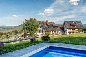 Una propiedad residencial con piscina, paneles solares y vistas a las colinas circundantes.