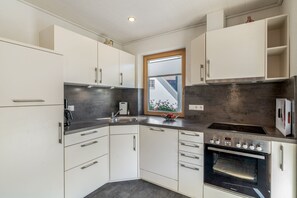 A modern kitchen with white cabinets, a built-in oven, and a window with a view of the outside.