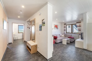 Una sala de estar moderna con un sofá, una mesa de centro y un televisor. Una escalera conduce a un nivel superior.