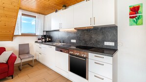 Une cuisine moderne avec des meubles blancs, un plan de travail noir, un lave-vaisselle et un four.