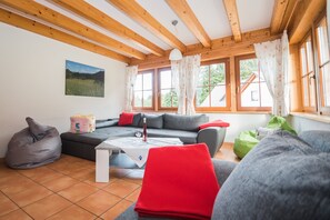 Un salon chaleureux avec un canapé d’angle, une table basse et un fauteuil poire.