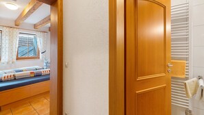 A wooden door leading to a room with a bed, a window with curtains, and a white radiator.