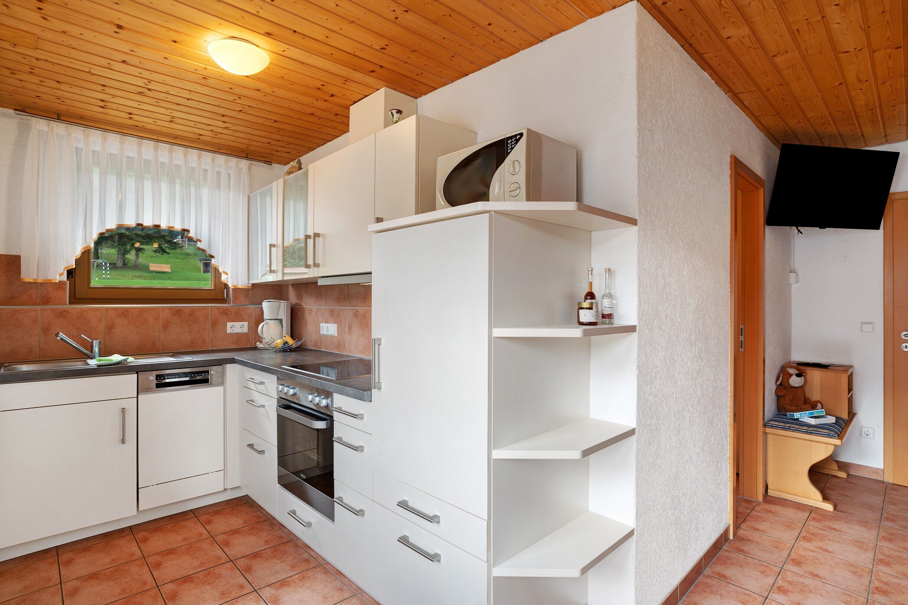 A compact kitchen with white cabinetry, a built-in oven, and a microwave.