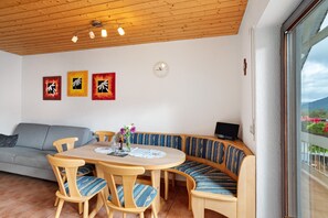 A dining area with a round table, wooden chairs, a bench, and a sofa.