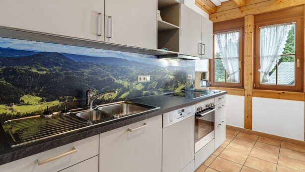 A kitchen with a mountain view mural, a sink, stove, and cabinets.