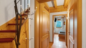 A wooden staircase with a metal railing, a wooden door, and a hallway leading to a room with a bed and a window. - Löcherhansenhof: Room 'Double Room 2' with Mountain View, Shared Terrace and Wi-Fi (Bad Peterstal-Griesbach)